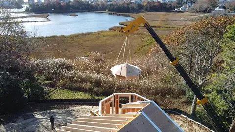 Crane lifting a cupola over a marsh-side job site