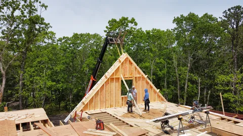 Crane lifting a framed gable wall into place
